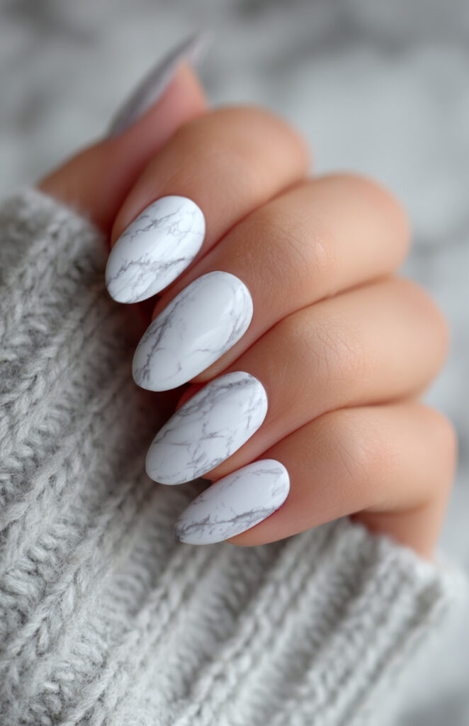 White marble nail art with soft gray veining on almond nails
