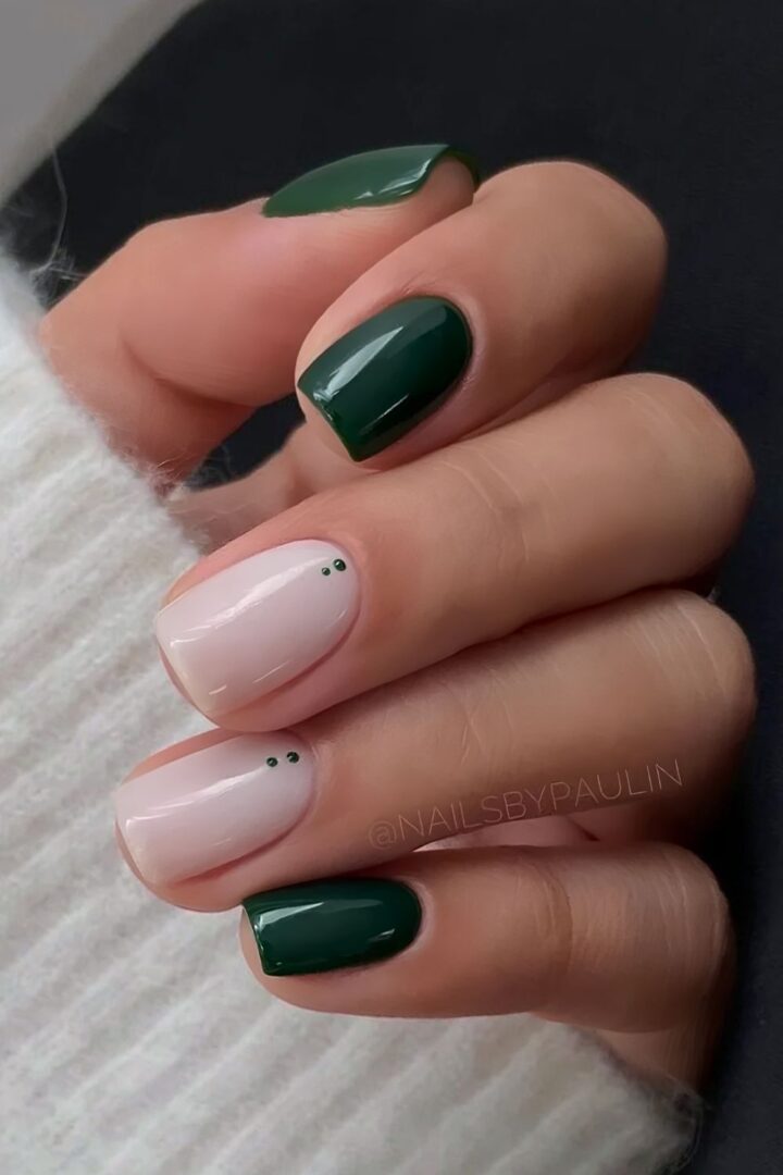 Short nails pairing deep evergreen green with milky white and tiny green dot accents