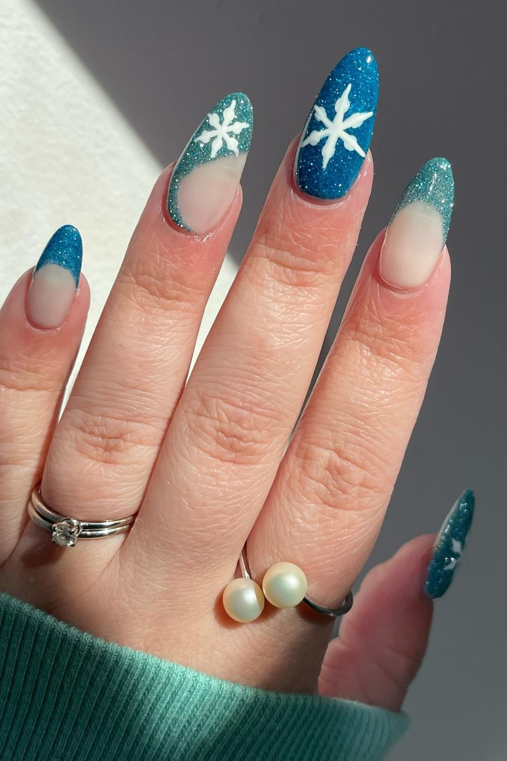 Almond nails with icy blue glitter French tips and white snowflakes
