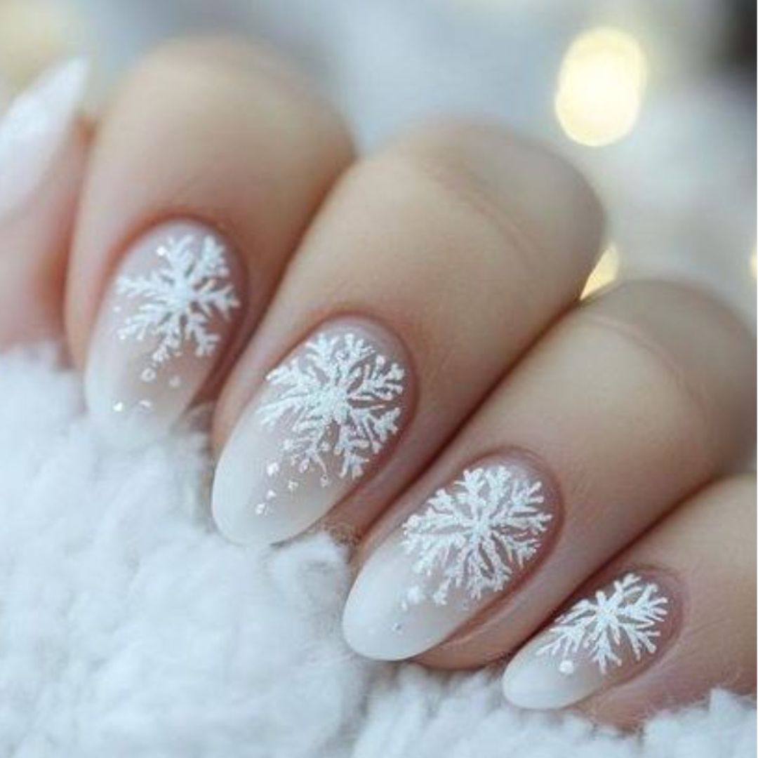 Almond nails with white snowflake designs on a milky pale-gray gradient base
