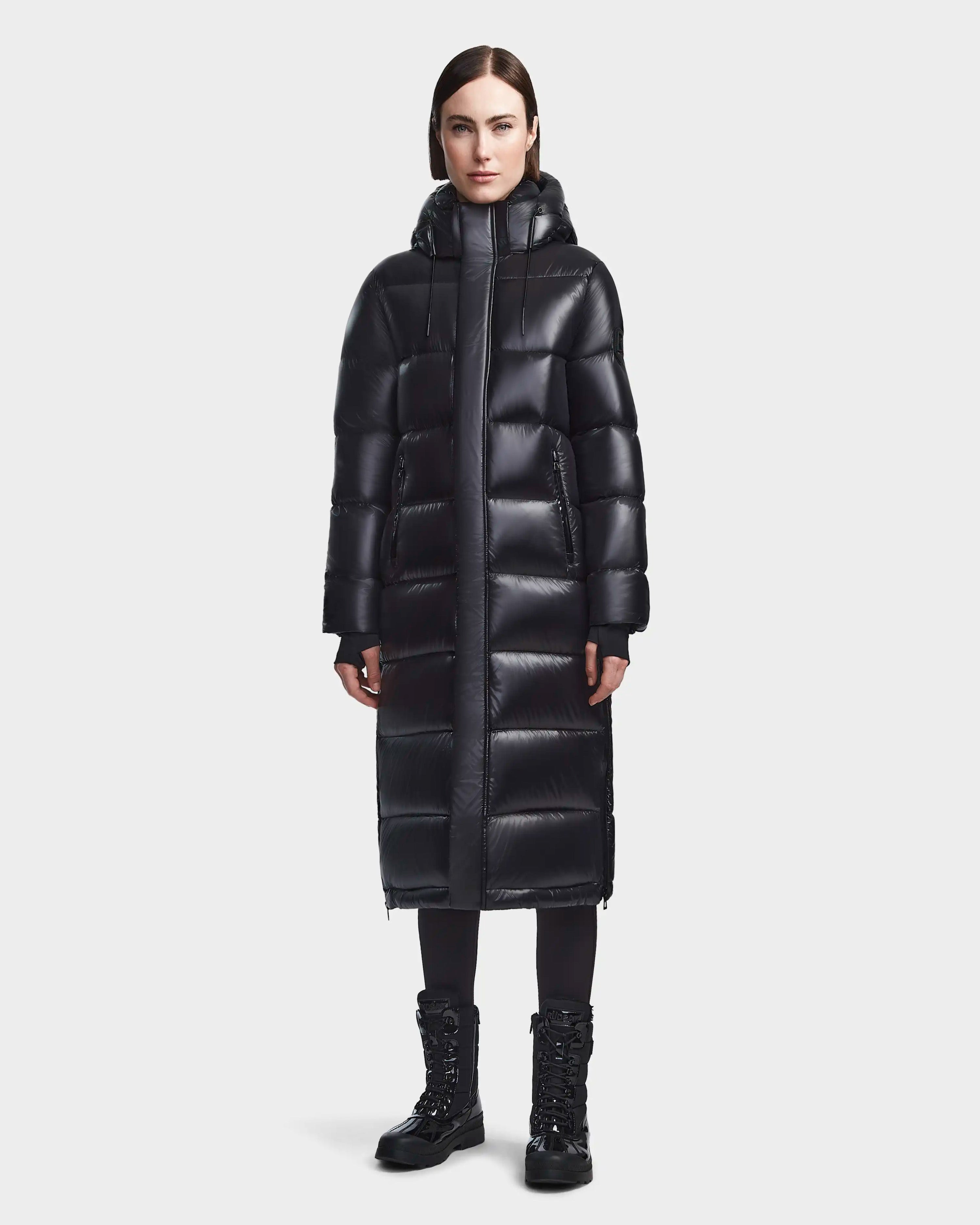 Model wearing a long black down puffer coat with black leggings and lace-up boots