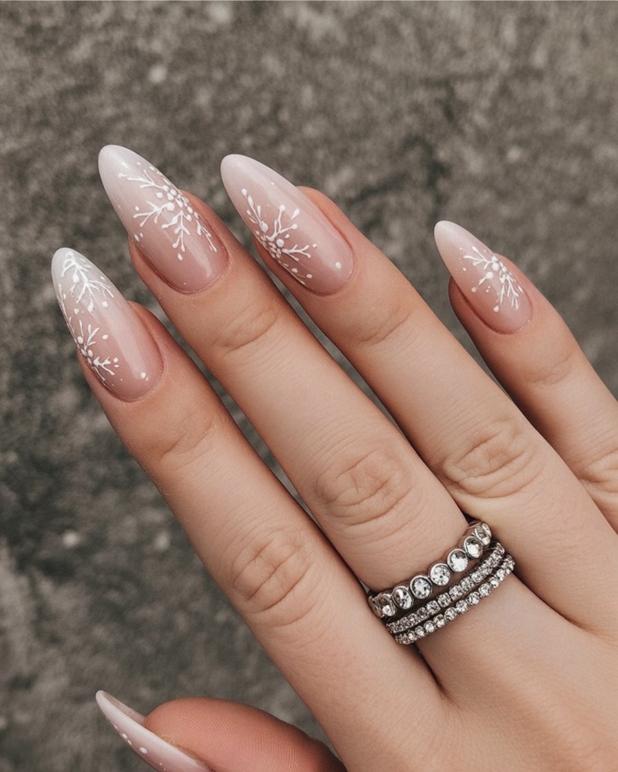 Sheer pink almond nails with white snowflake art near the tips