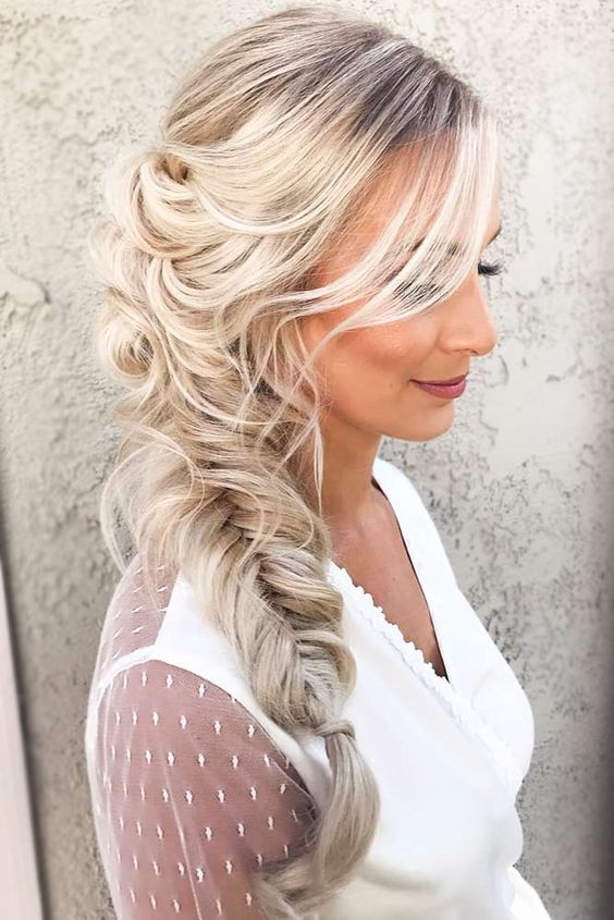 Relaxed low fishtail side braid with side bangs for a boho formal look