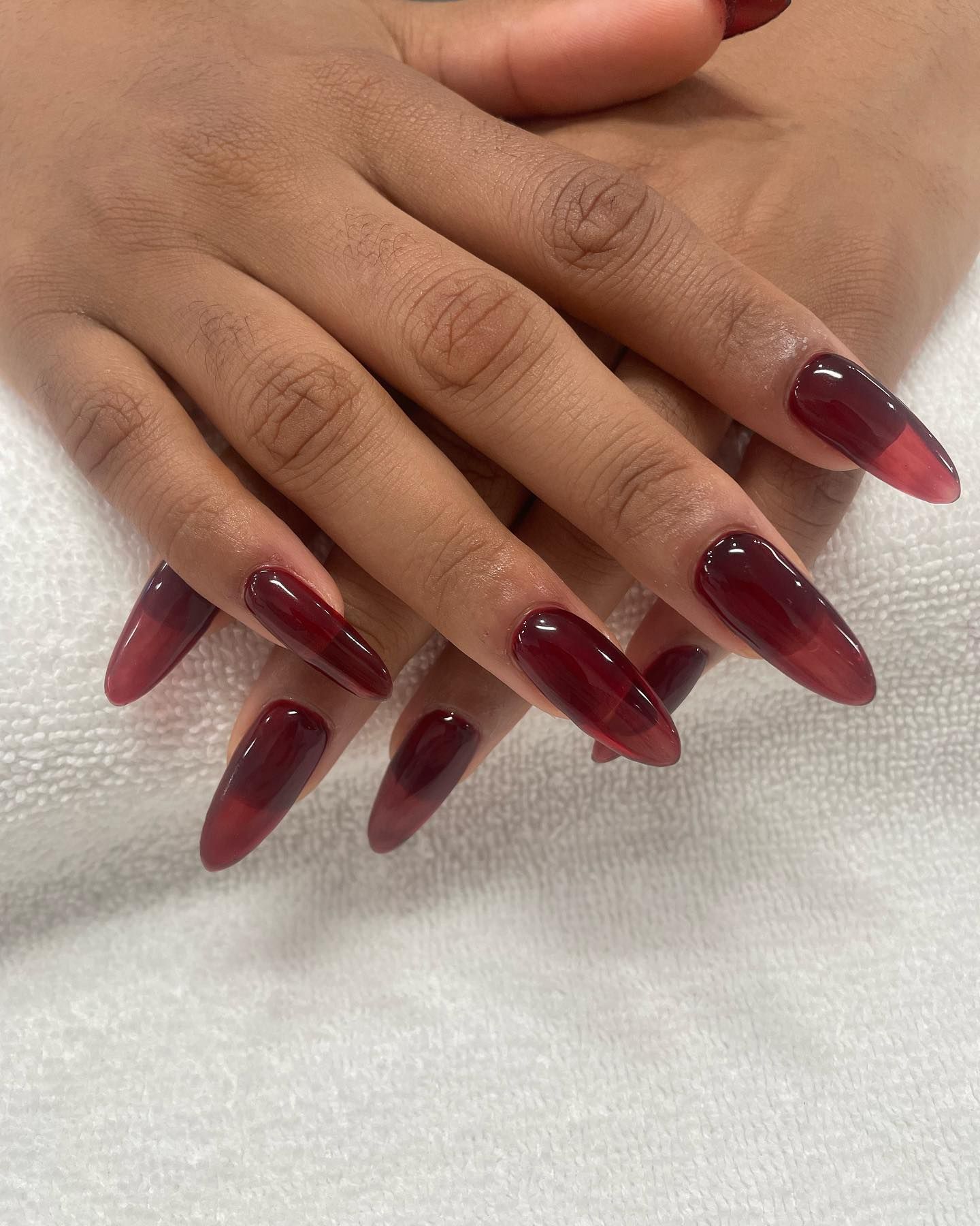 Long almond nails in a sheer translucent jelly wine-red finish with high gloss