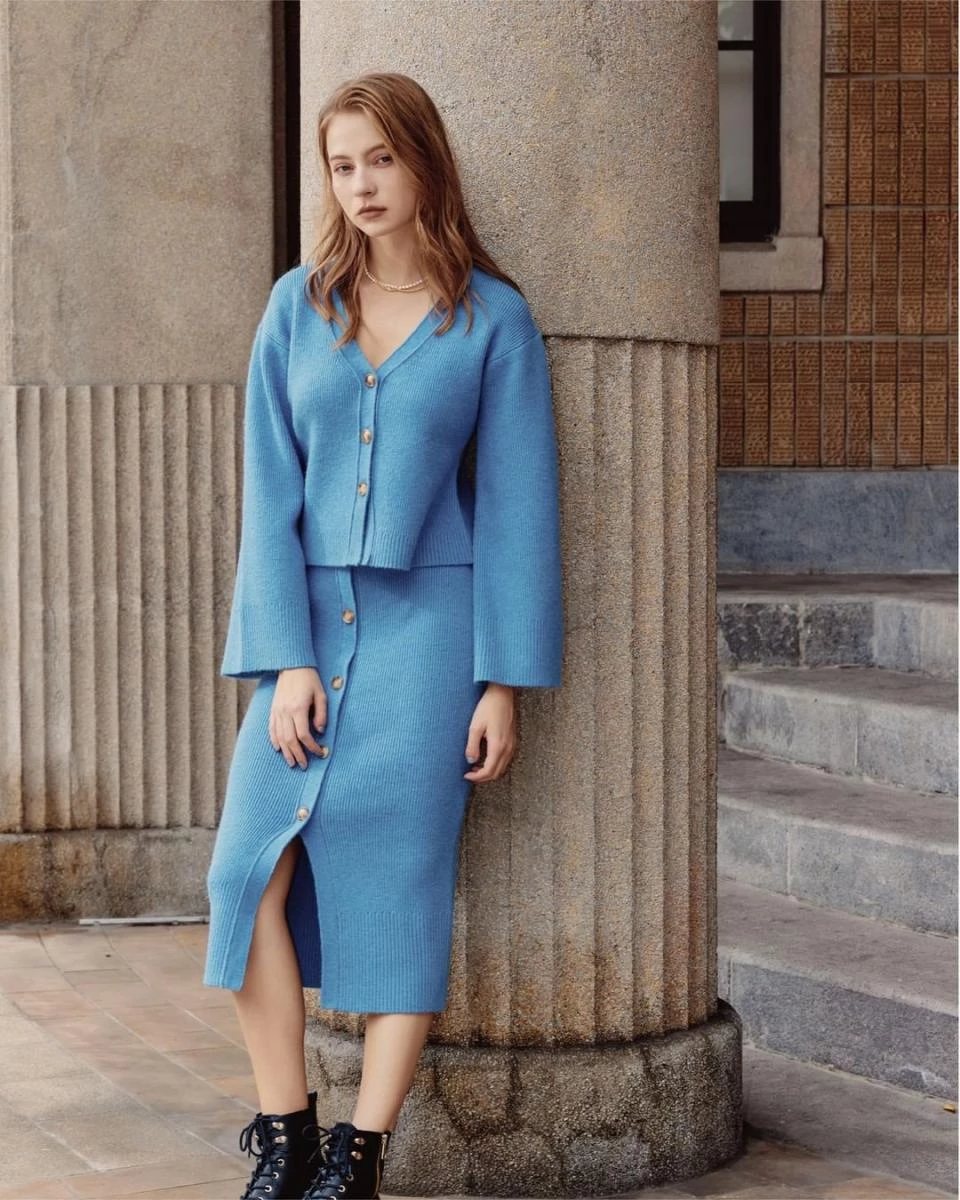 Woman wearing a cornflower blue cardigan with a matching blue button-front midi skirt and black lace-up boots