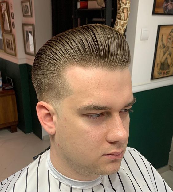 Man with a glossy classic pompadour haircut and tapered sides