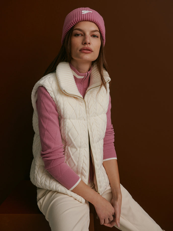 Woman wearing a cream cable-knit gilet layered over knit separates