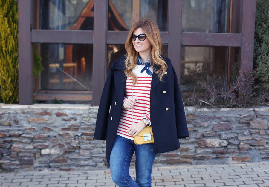 Woman wearing a navy double-breasted peacoat, striped sweater and jeans winter outfit