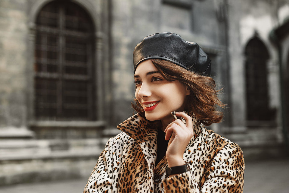 Woman wearing a black leather beret with a leopard print faux fur coat