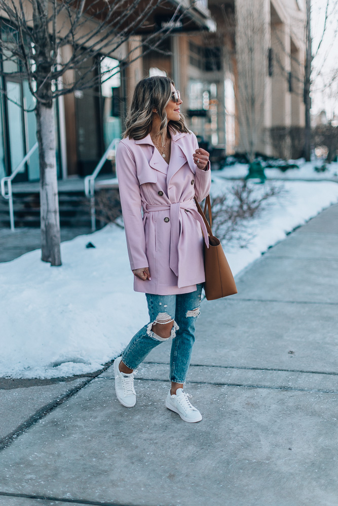 Woman wearing a blush pink trench coat over white winter layers