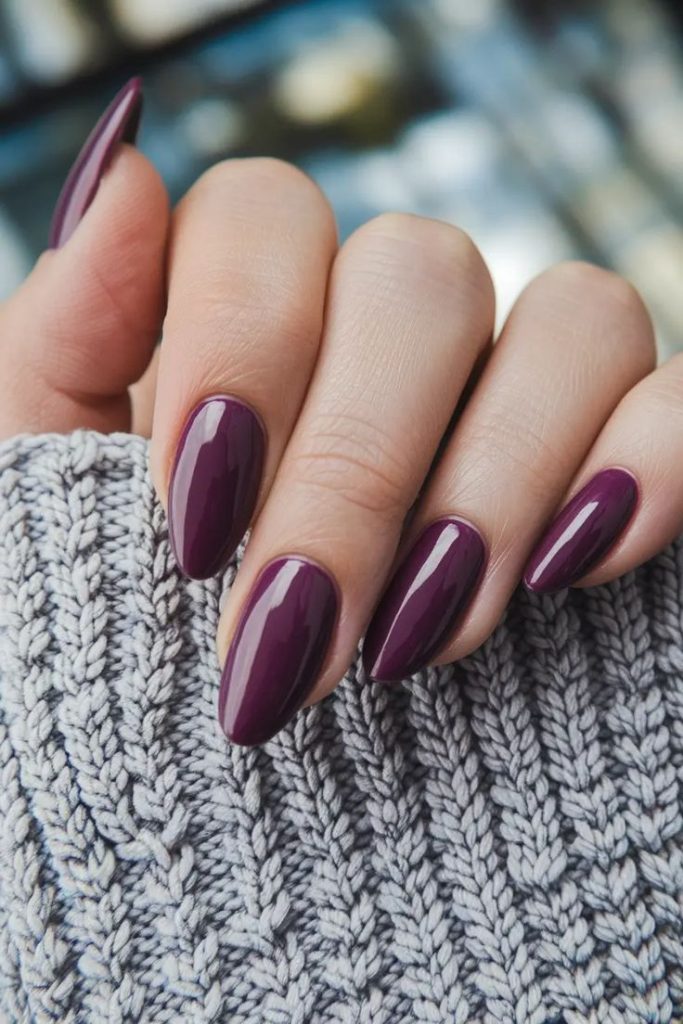Deep plum glossy nails in an almond shape