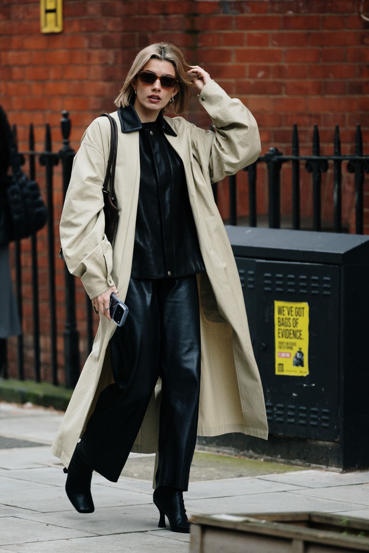 A woman in a cream trench coat with a leather collar over black leather separates on a London street