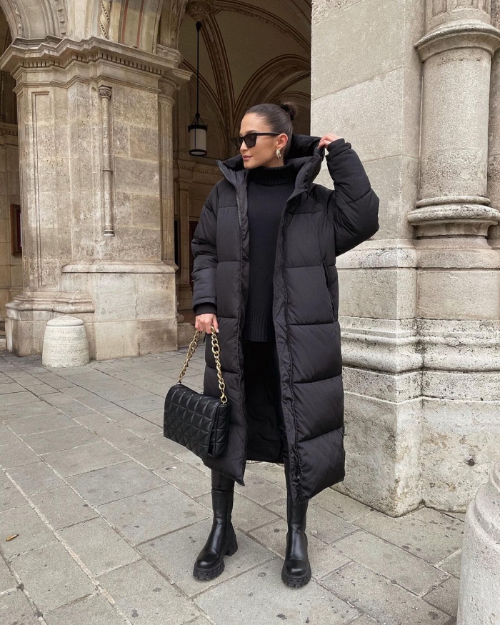 Woman in a long black puffer coat with a black turtleneck, black trousers and chunky boots