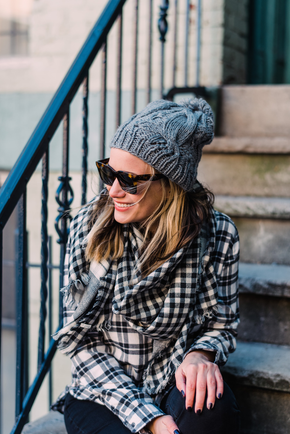 Woman in a grey cable-knit beanie with a buffalo plaid scarf