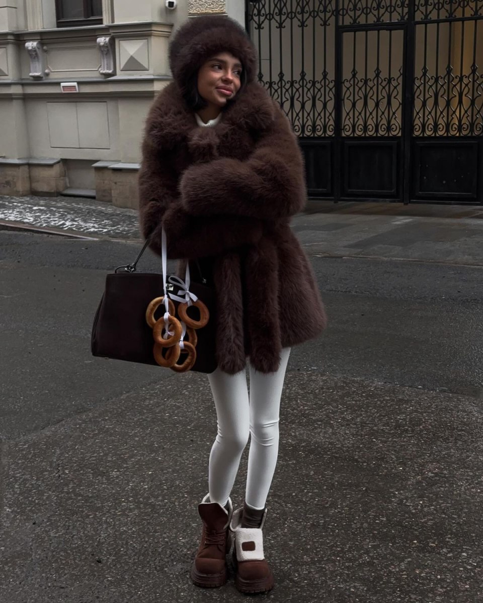 Woman in a chocolate brown fur hat and brown fur coat with white tights and brown boots