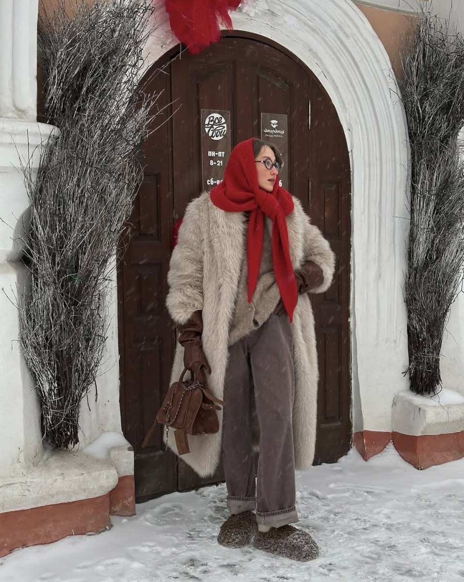 Woman in a snowy street wearing a red headscarf tied babushka-style under the chin with a fur coat