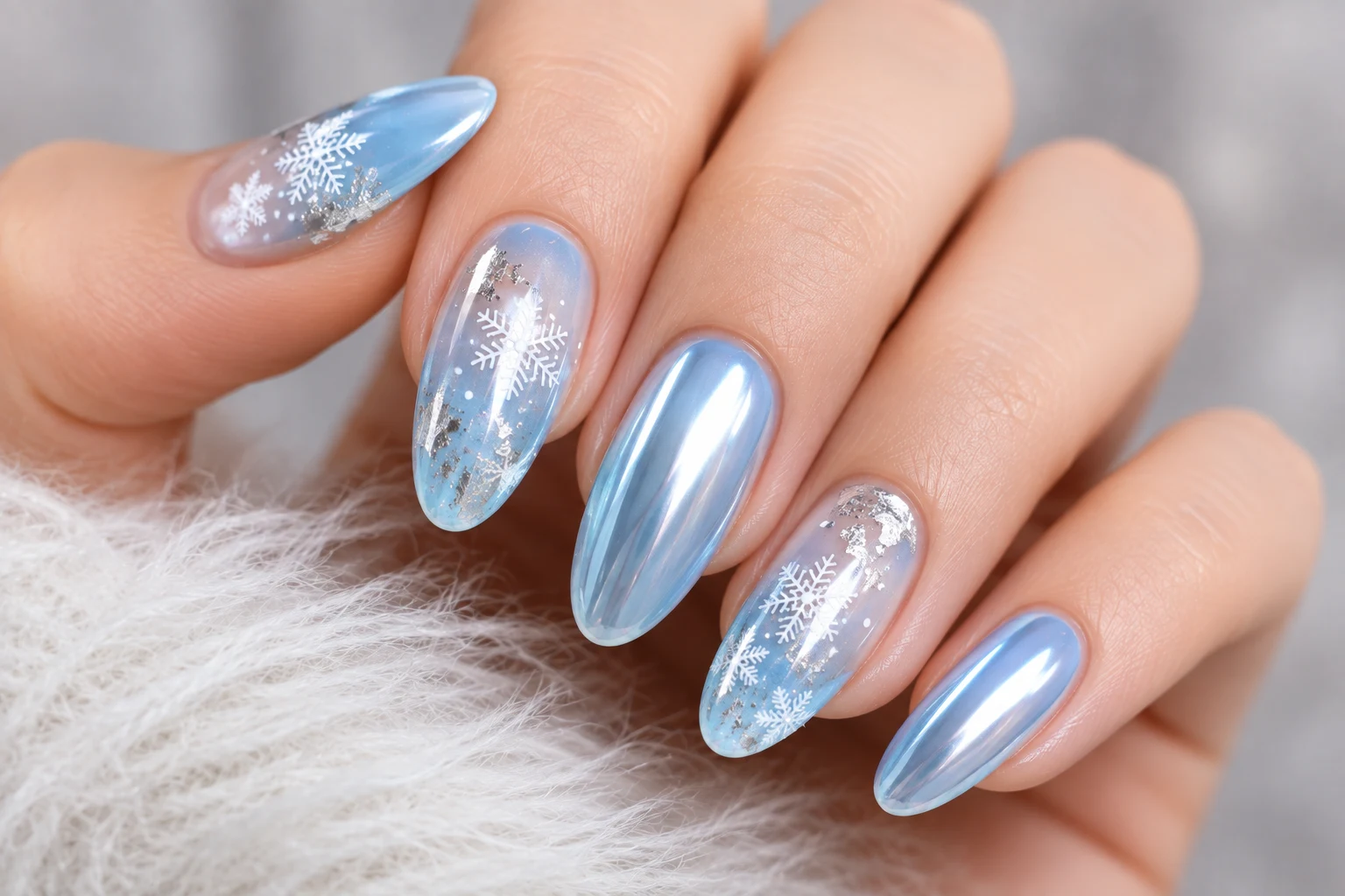 Long almond nails in icy blue chrome alternating with sheer nails stamped with snowflakes and silver foil