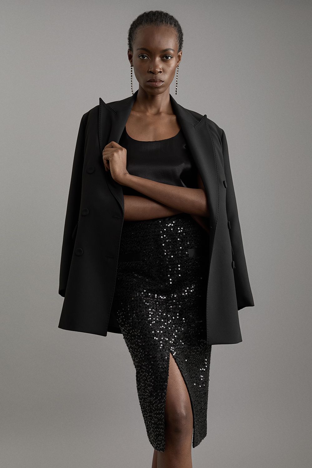 Black sequin midi skirt with front slit, black satin top and black blazer draped over shoulders