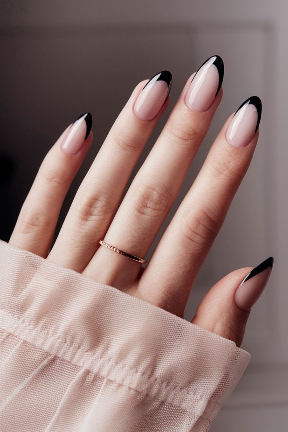 Almond nails with sheer nude base and thin black french tips