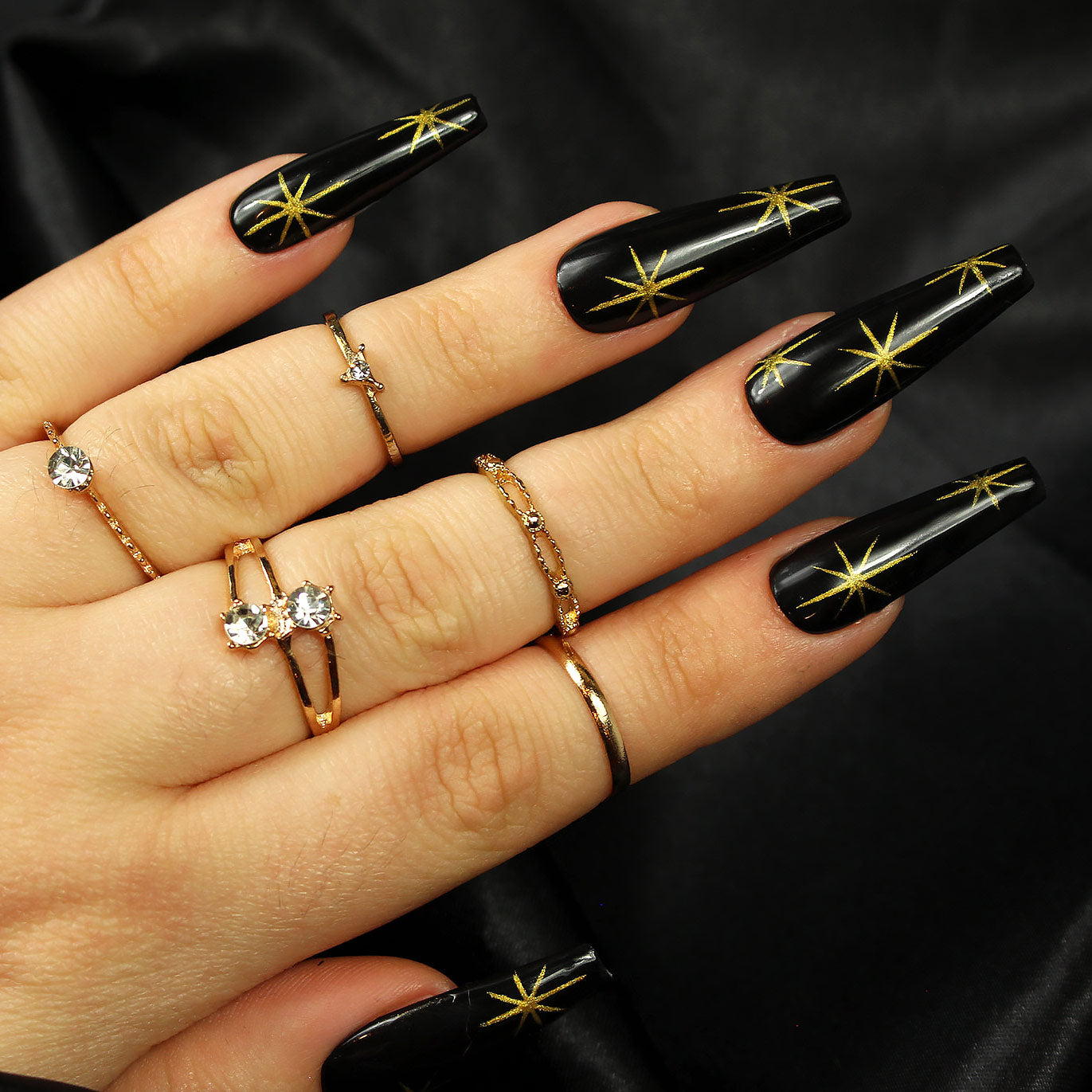 Long coffin nails in glossy black with gold starburst nail art