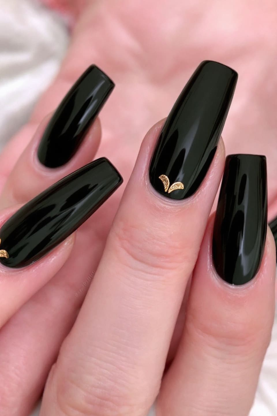 Black nails with gold half-moon accents at the base