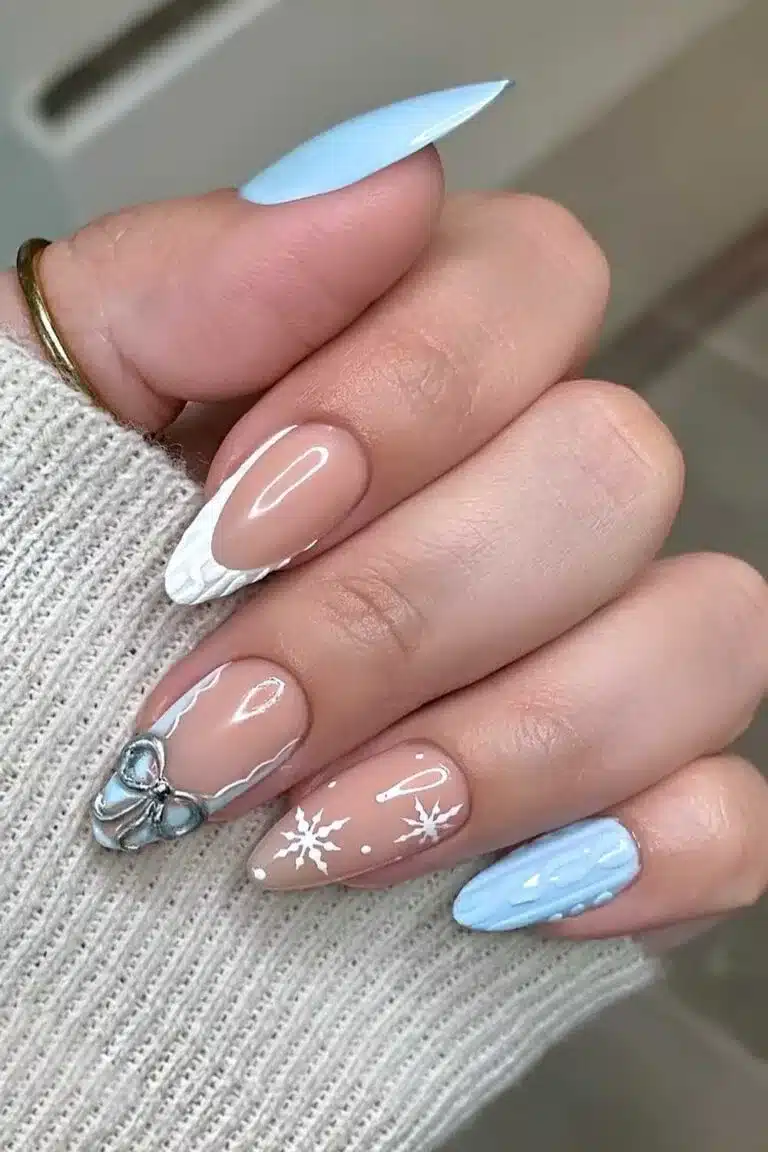 Long almond nails mixing baby blue, nude with snowflakes, cable-knit texture and a bow charm