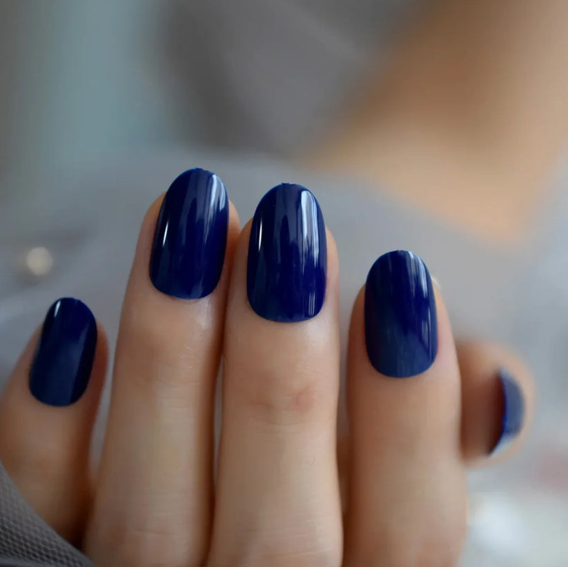 Short almond nails painted in glossy deep navy blue