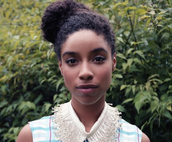 Woman with a high rounded bun showing natural coily texture, very dark brown hair.