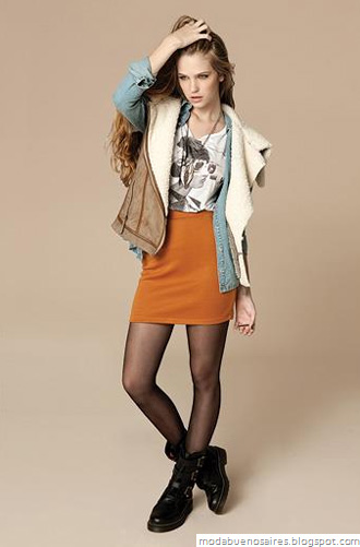 Woman in a burnt-orange mini skirt, denim shirt, shearling vest, black tights and black combat boots