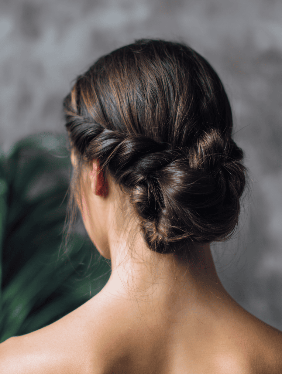Rope/twist braid woven into a low bun on caramel-brown hair, back view.