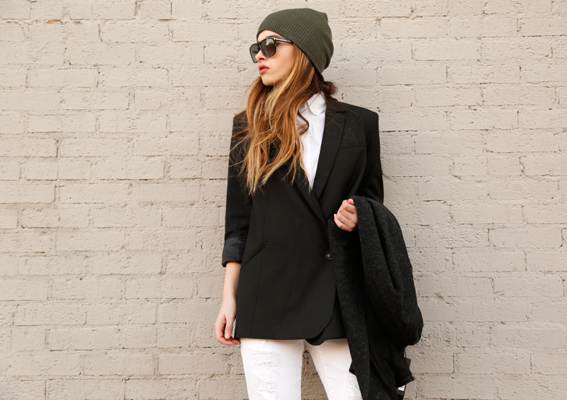 Woman in an olive beanie, black blazer, white shirt and white jeans