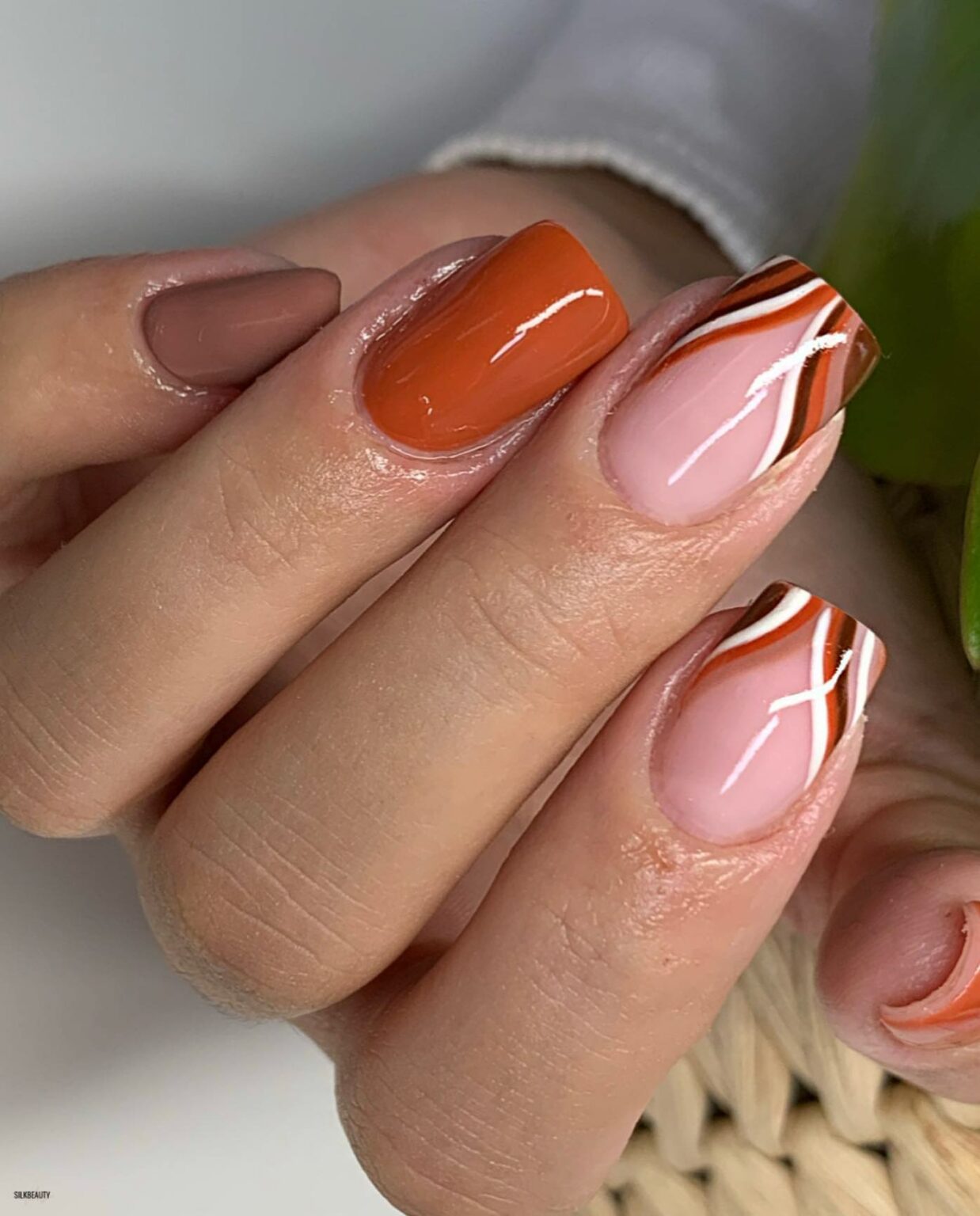 Short square nails in burnt orange with cream swirl art