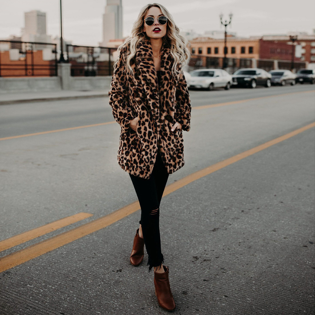 Woman in a leopard faux fur coat with black ripped jeans and brown ankle boots