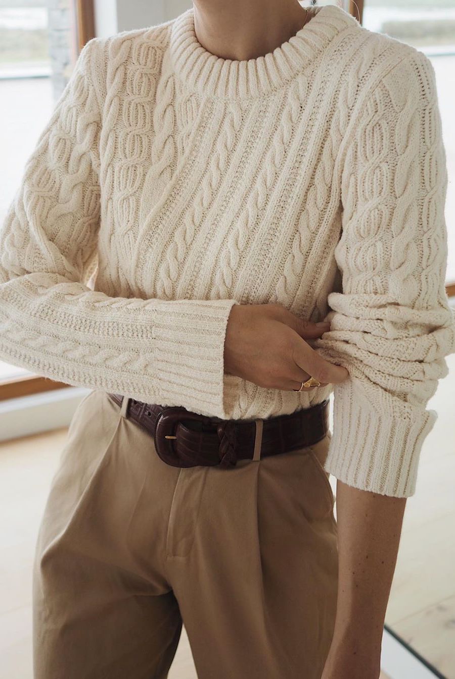 Cream chunky cable-knit sweater paired with tan wool trousers winter outfit