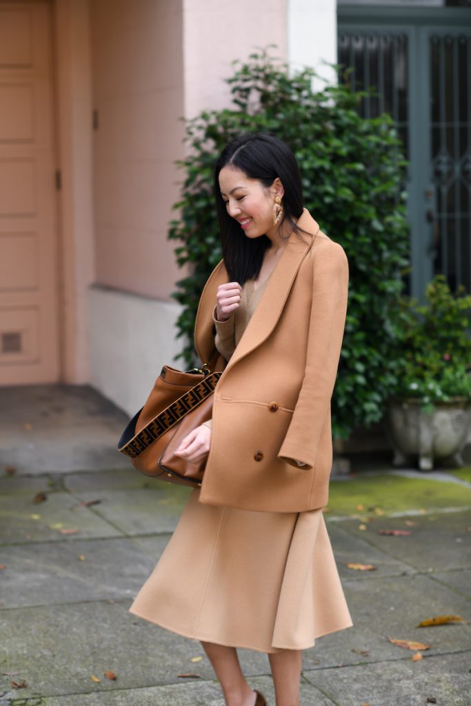 Fashion blogger wearing a camel double-breasted peacoat with a matching camel midi skirt and brown leather bag