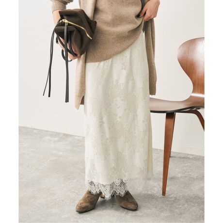 Woman in brown suede ankle boots with a beige cardigan and white lace maxi skirt