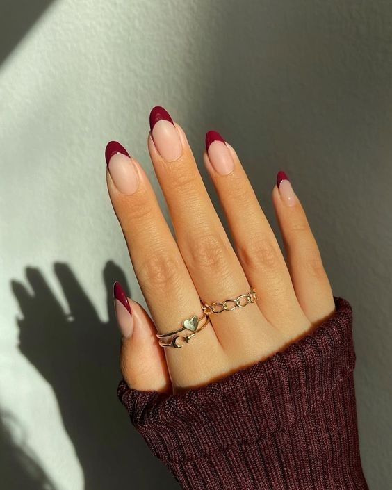 Short oval nails with wine-red French tips on a sheer nude base