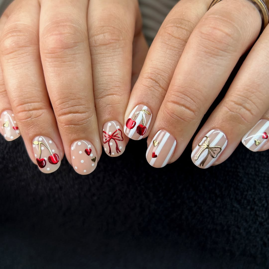 Nude nails with cherry, bow, heart, dot, and stripe nail art