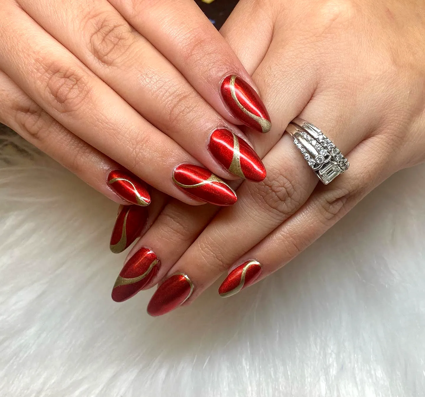 Almond nails in metallic red chrome with wavy gold stripes