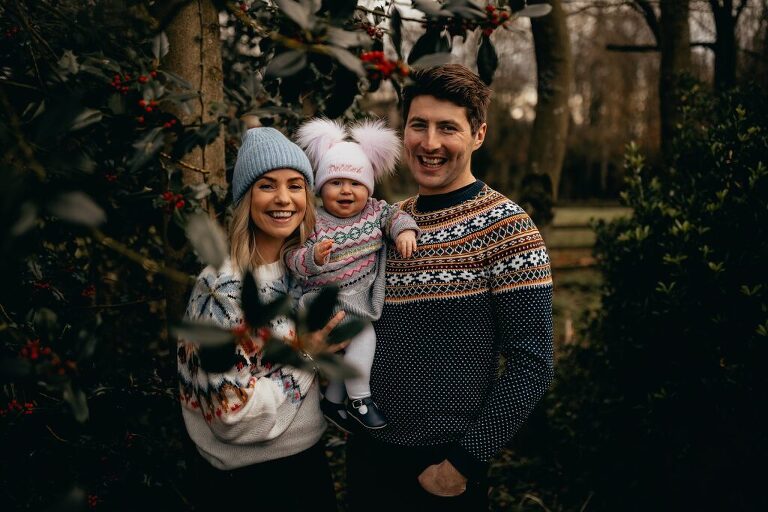 Family in cozy holiday knitwear at a Christmas doorstep photo session