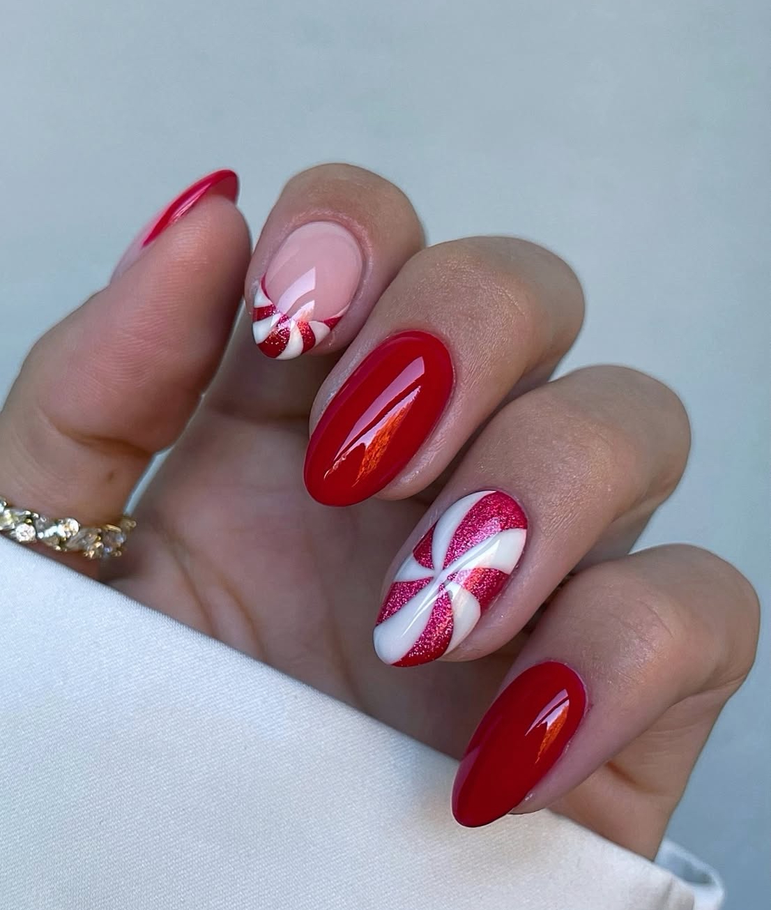 Glossy red almond nails with peppermint swirl accent nails