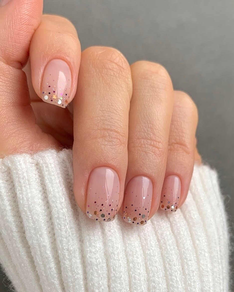 Sheer nude nails with scattered glitter at the tips