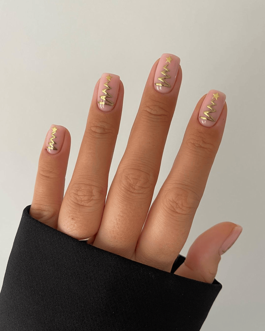 Nude nails with gold zigzag Christmas tree line art and star toppers