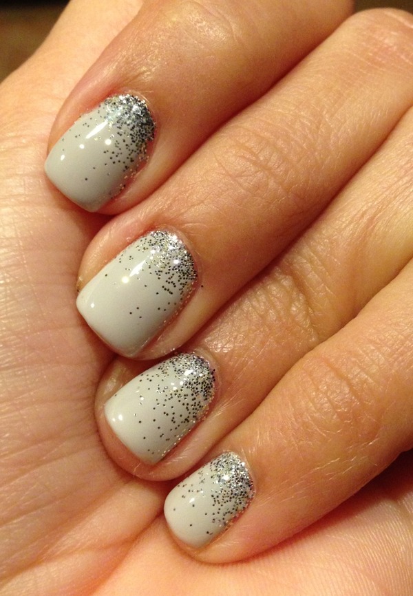 Short squoval nails in light gray with silver glitter fading in from the tips