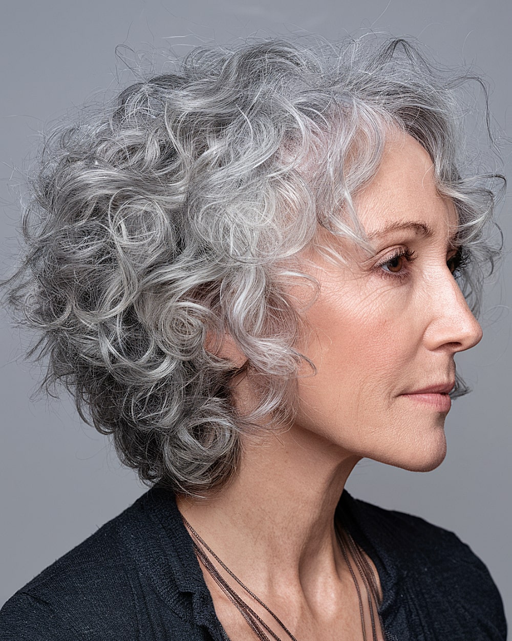Short gray curly crop hairstyle with playful volume