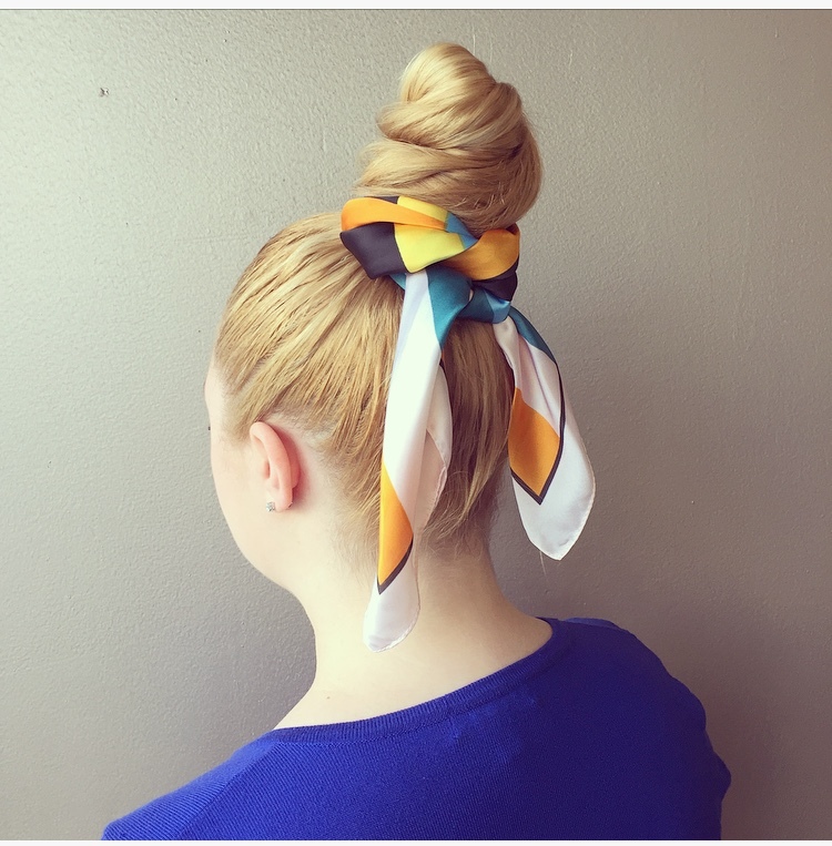 Woman with a high topknot wrapped with a printed silk scarf