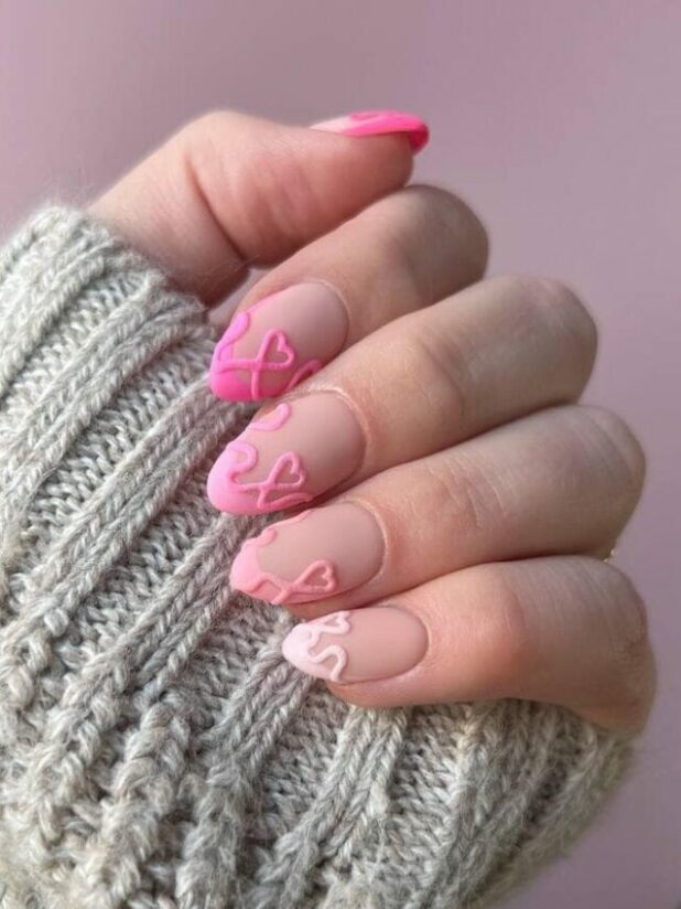 Almond nails with sheer nude base and raised pink 3D hearts
