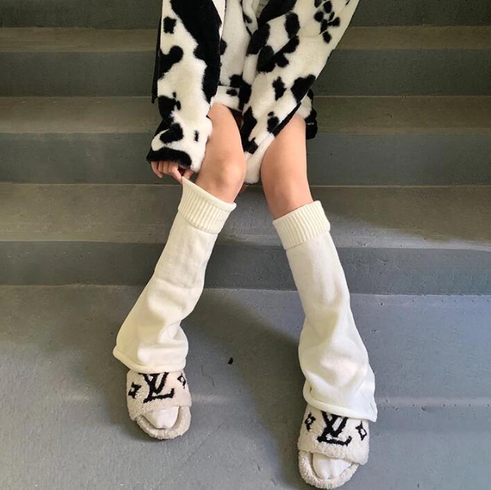White ribbed leg warmers worn with a black and white cow-print faux fur coat and cream embroidered slides