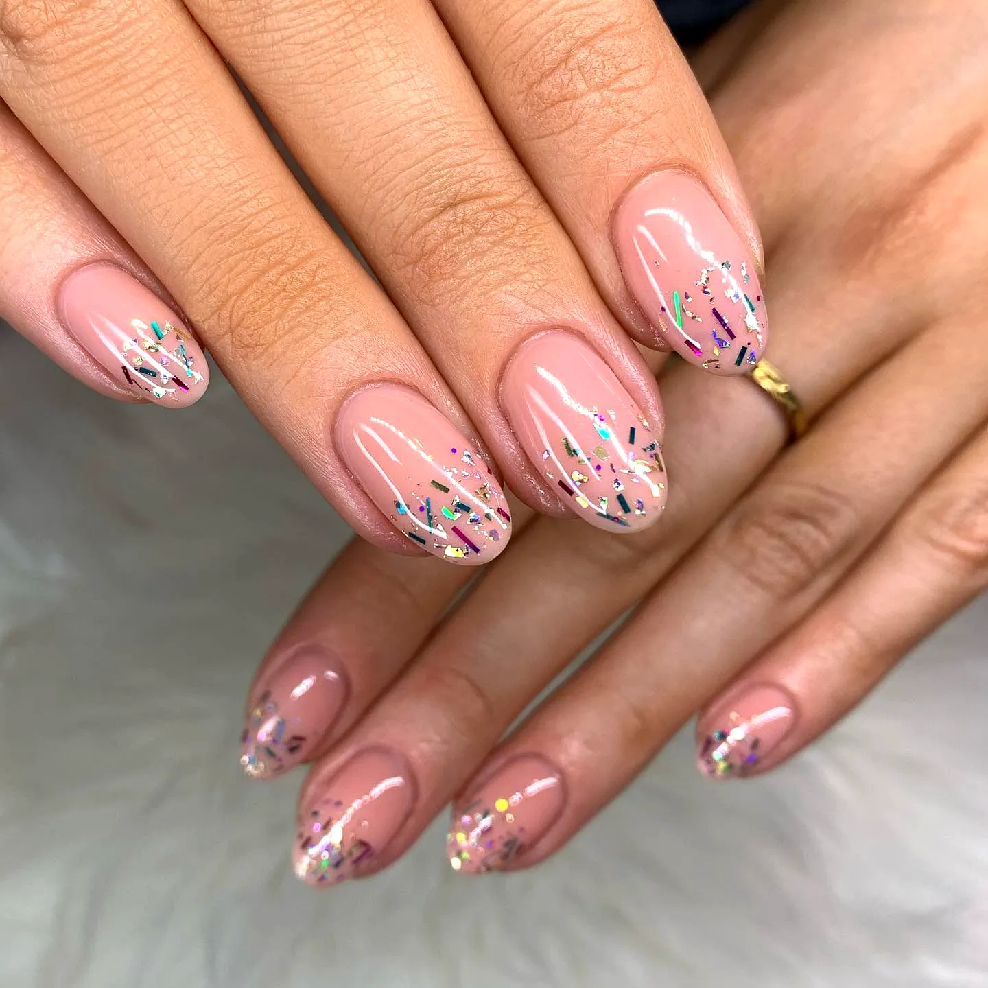 Almond nails with nude pink base and multi-colored confetti glitter gradient