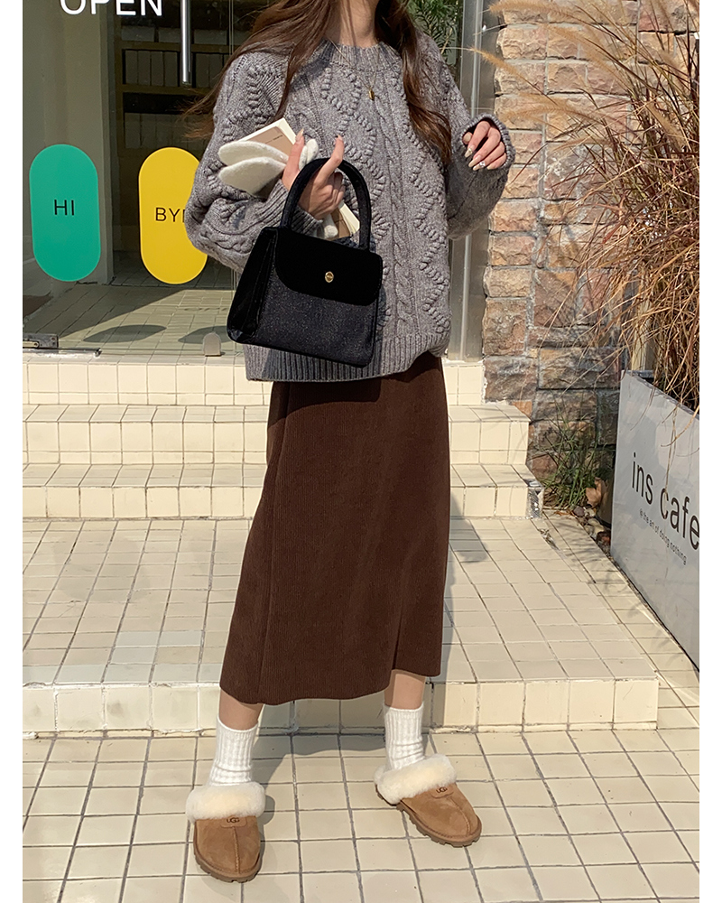 Woman wearing chestnut Ugg Scuffette slippers with a grey cable-knit sweater and brown corduroy midi skirt